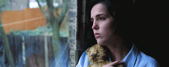 Sad young woman holding teddy bear