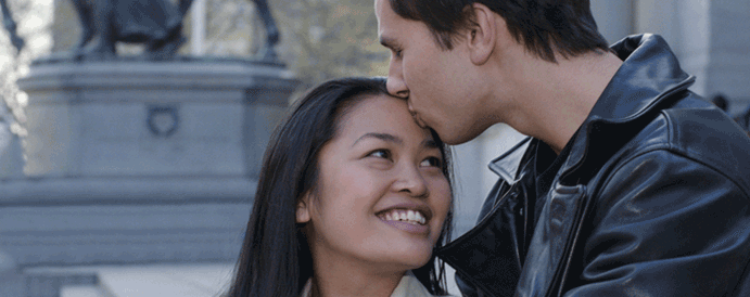 A young man kissing a smiling young woman on the forehead