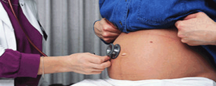 A doctor placing a stethoscope on a pregnant woman's belly